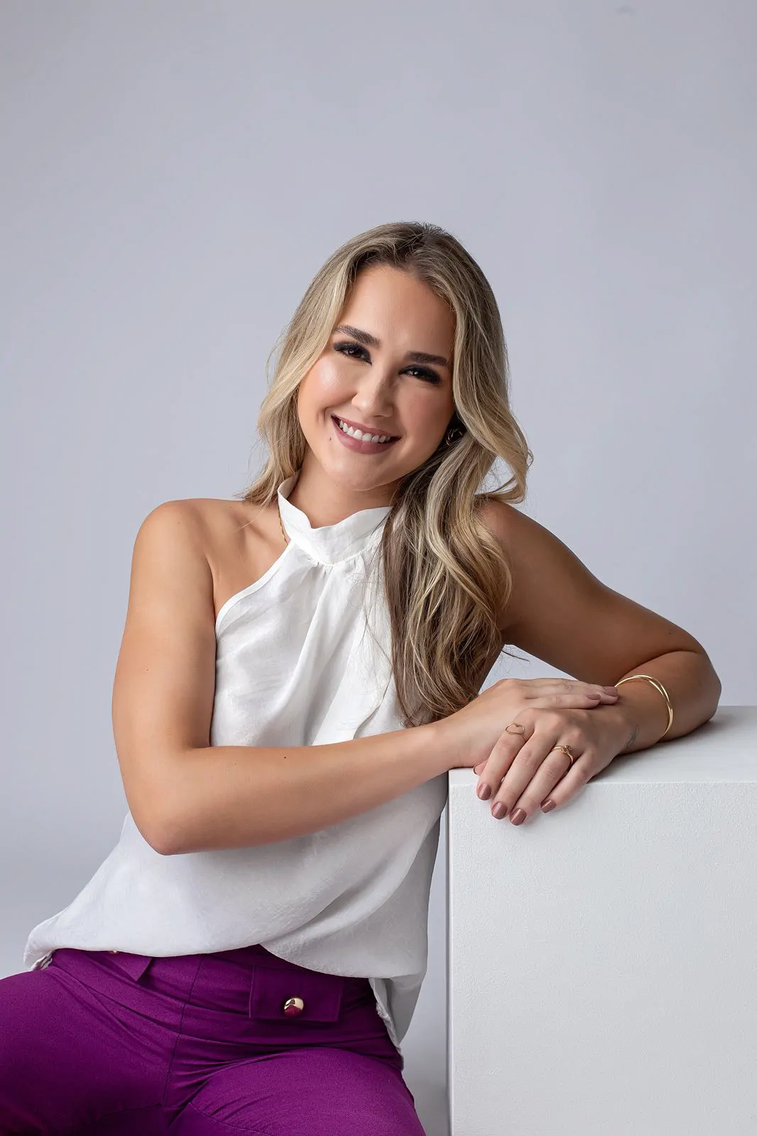 Sofia Schlemper Maciel sorrindo, com o braço apoiado sobre um cubo branco.